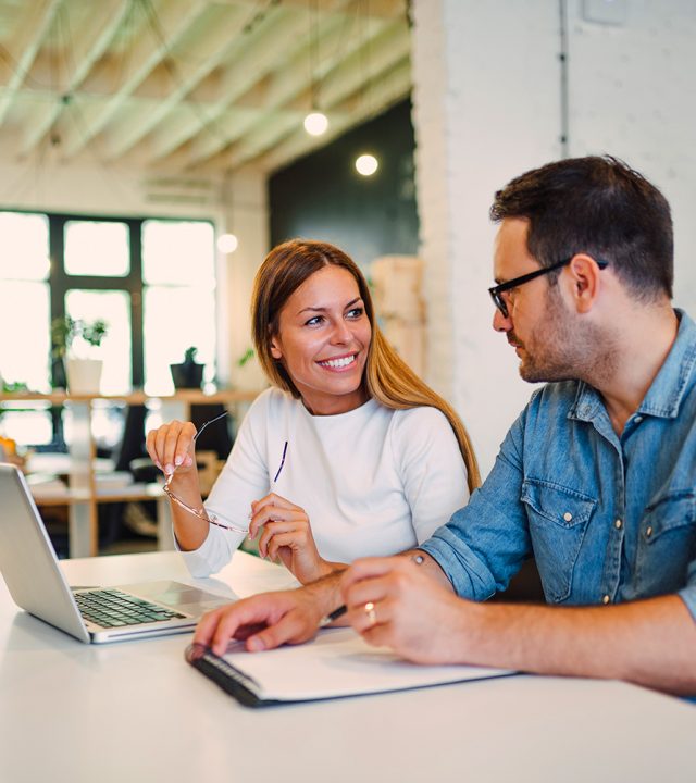 Two coworkers discussing during working process in modern office.